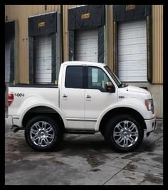 a white pick up truck parked in front of a building with roller doors on it's sides