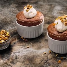 three cupcakes with whipped cream and nuts on top