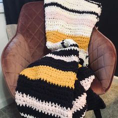 a crocheted blanket sitting on top of a brown chair