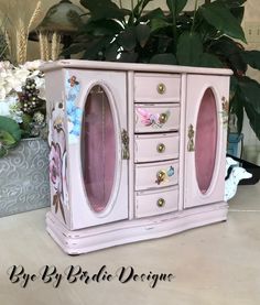 an old dresser has been painted pink with flowers and butterflies on the doors, along with other decorative items