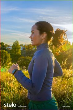 a woman is running in the grass with her hair blowing in the wind and looking off into the distance