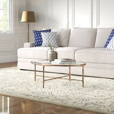 a living room with white couches and blue pillows on the sofas, along with a coffee table