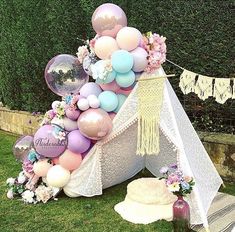 a tent with balloons and flowers on the grass