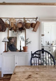 a wooden table sitting under a mirror next to a wall mounted pot rack with baskets on it