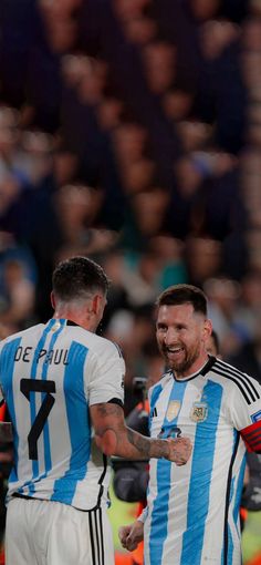 two men in blue and white uniforms standing next to each other on a soccer field