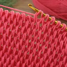 a close up view of the stitches on a knitting machine with yarn in the background