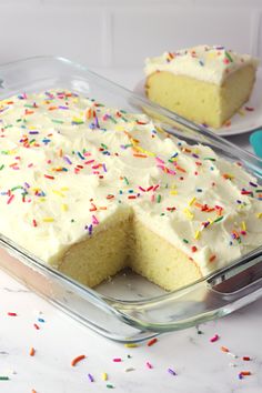 a cake with white frosting and sprinkles in a glass baking dish