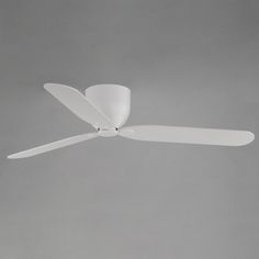 a white ceiling fan in the middle of a gray room with light coming from it