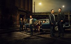 a group of people standing in front of a car at night with the lights on