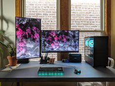 two computer monitors sitting on top of a desk next to a keyboard and monitor screen