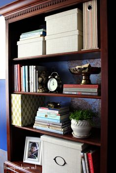 a bookshelf filled with lots of books on top of a wooden shelf next to a wall