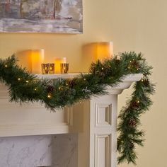 a decorated mantle with candles and garland on it