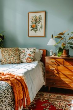 a bedroom with blue walls and an orange blanket on the bed next to a dresser