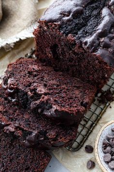 a loaf of chocolate cake sitting on top of a cooling rack next to a bowl of chocolate chips