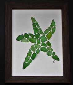 a green sea glass starfish in a brown frame on a white background with black border