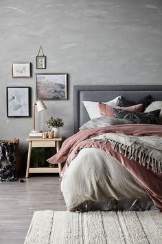 a bedroom with grey walls and wooden flooring is decorated in shades of pink, gray and white