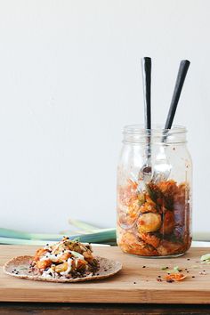 a jar filled with food sitting on top of a wooden table next to a plate