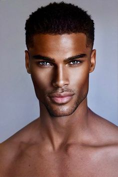 a close up of a shirtless man with short hair and blue eyes looking at the camera