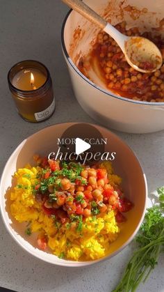 a white bowl filled with beans and rice next to a candle on top of a table