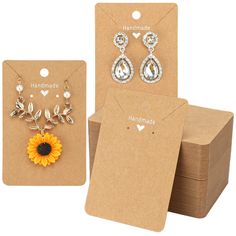 three pieces of jewelry are shown in front of a cardboard box and two cards with the same