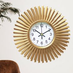 a clock that is sitting on the wall next to a chair and potted plant