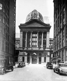 an old black and white photo of cars parked in front of a building with a dome on top