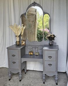 an antique vanity with two drawers and a large mirror on the top, in front of a curtained window