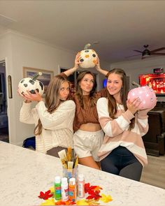 three girls are holding up piggy banks in the kitchen