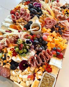 an assortment of cheeses, fruits and meats on a platter