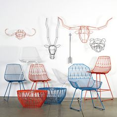 several different colored chairs in front of a white wall