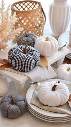 white and black pumpkins are sitting on plates in front of other fall decor items