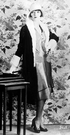 an old photo of a woman standing next to a table