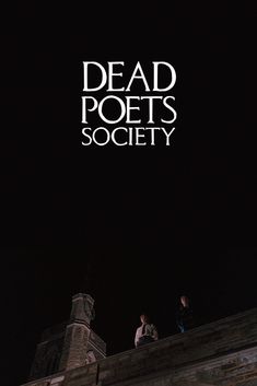 two people standing on top of a building at night with the words dead poets society above them