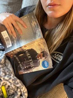 a woman sitting on a couch holding a book