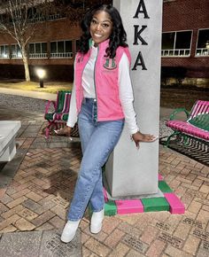 a woman standing next to a statue in front of a bench with pink and green chairs