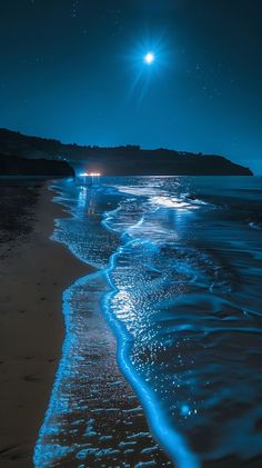 the beach is lit up at night with bright blue waves and stars in the sky