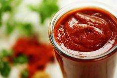 a glass filled with sauce sitting on top of a table