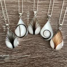 four pendants with different designs on them sitting on a wooden surface, one is white and the other is brown