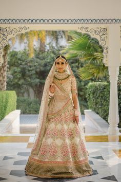 a woman in a bridal gown standing on a tiled floor with palm trees behind her