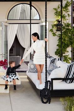 a woman standing on top of a bed next to a little boy in a black and white dress