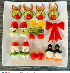 an assortment of food on a white plate with red bows and green vegetables in the shape of santa hats