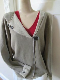 a mannequin wearing a sweater with buttons on the front and back, standing next to a white door