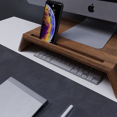 an iphone is sitting on top of a wooden stand next to a keyboard and mouse