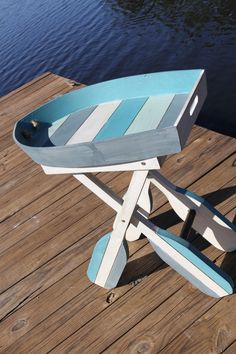 a small blue and white boat shaped table on a wooden dock next to the water