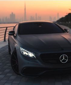 the front end of a black mercedes benz coupe parked in front of a city skyline