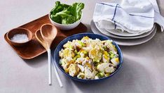 a blue bowl filled with salad next to two wooden spoons