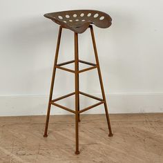 a wooden stool sitting on top of a hard wood floor next to a white wall