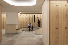 a man sitting on a bench in the middle of a room filled with wooden lockers