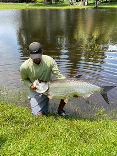 a man kneeling in the water holding a fish