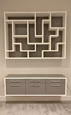 a white shelf with drawers and shelves on it's sides in front of a gray wall